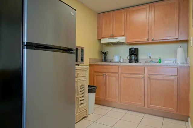 The kitchenette with a stainless refrigerator, wood cabinets, a microwave and a coffee maker
